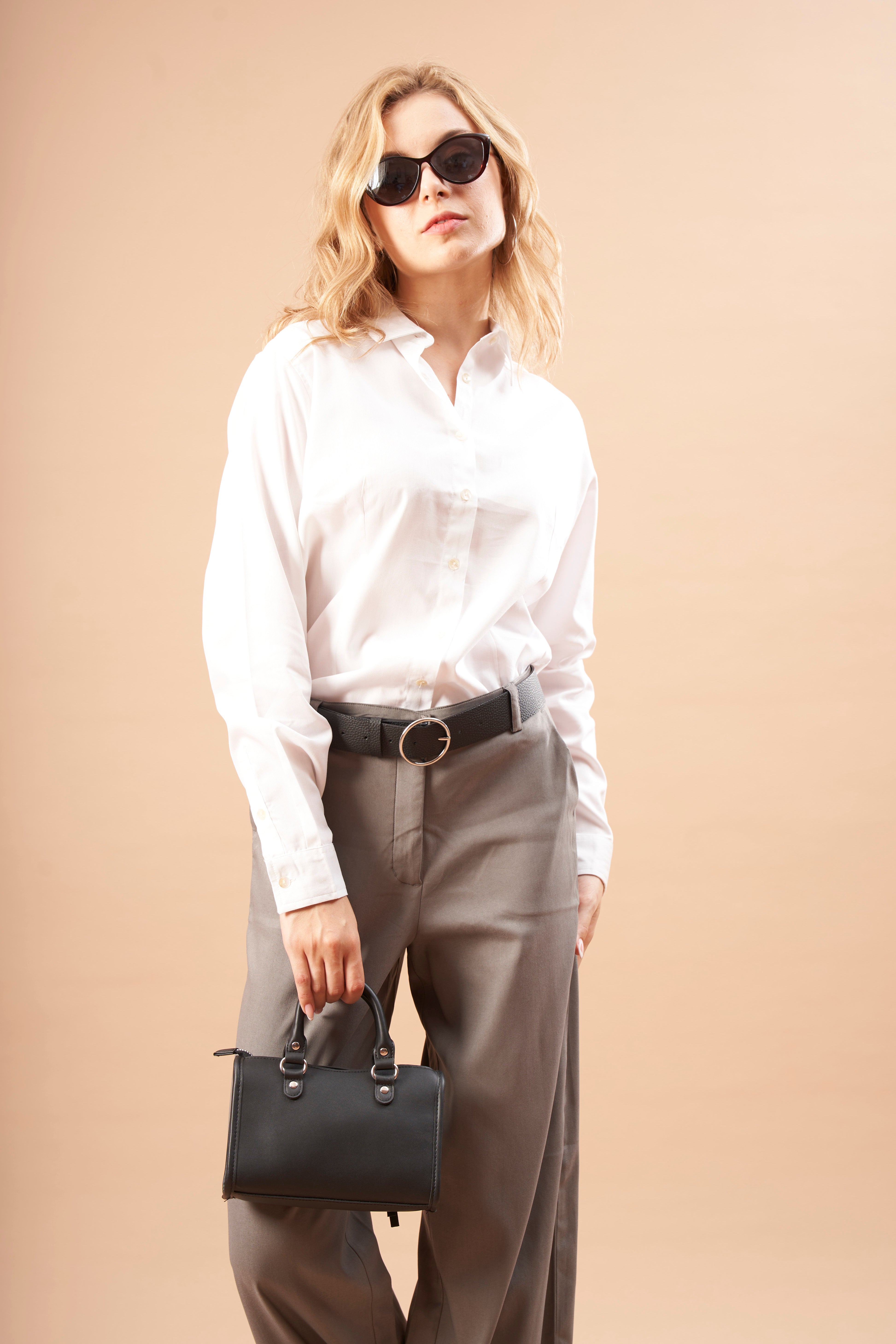 A woman walks in a Cotton White Shirt with pocket from Gazillion with rolled up hem denims and a pink blazer on her shoulder